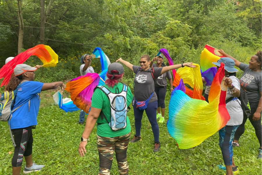 Women gathered in a circle waving rainbow colored fabric