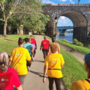 Group of women walking in colorful shirts on a trail along a river