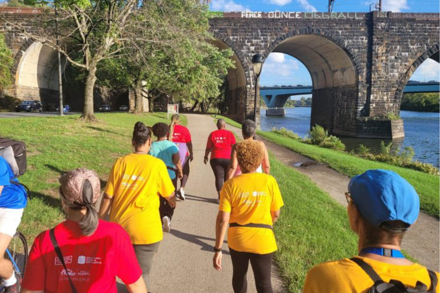 Group of women walking in colorful shirts on a trail along a river