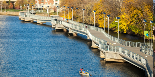 Photo of the trail and water, a man kayaks near the bottom of the image.